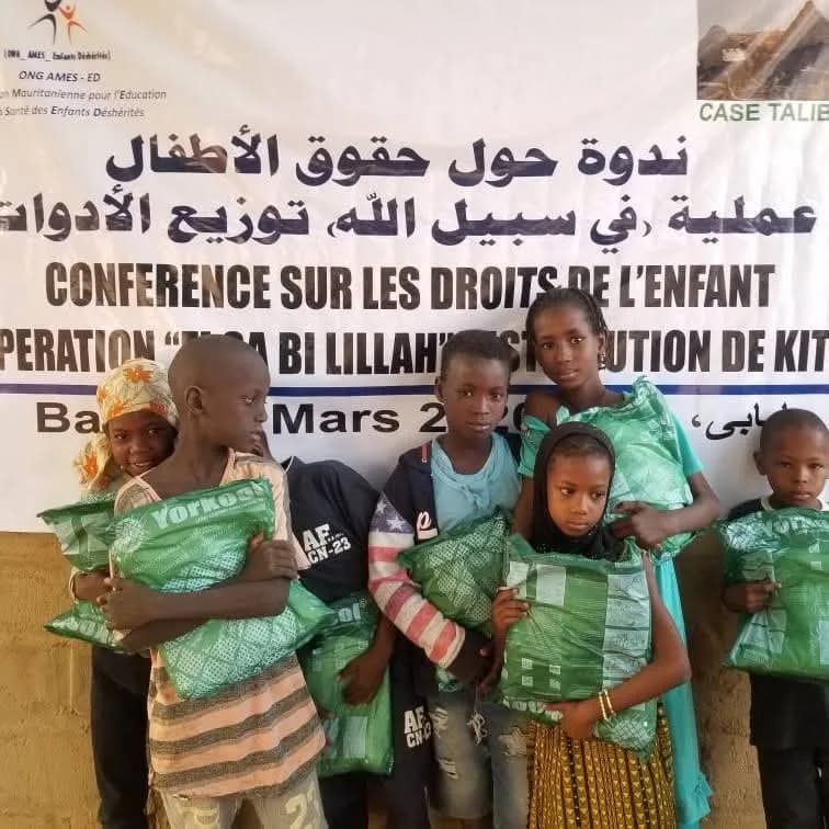 Enfants tenant leurs kits devant la banderole d'AMES-ED, lors d'une conférence sur les droits de l'enfant